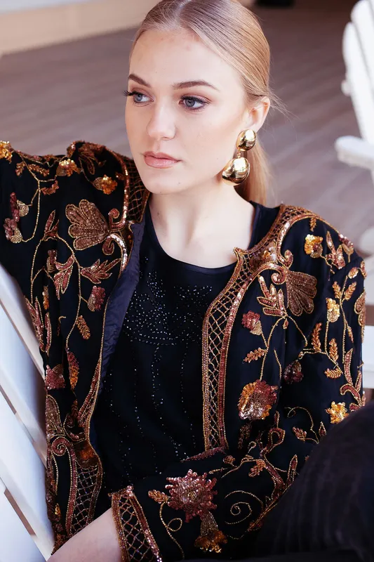 Editorial makeup by Gatsby on a blonde model wearing a heavily embellished black jacket and gold earrings.