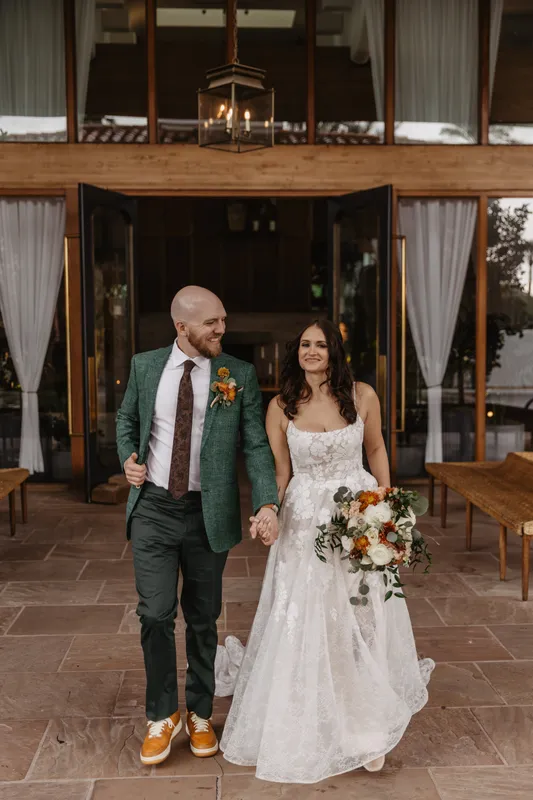 Newlywed couple smiling while walking together, showcasing bridal makeup by Gatsby.